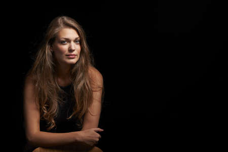 Natural beautiful woman with flowing hair leaning on elbow over black backgroundの写真素材