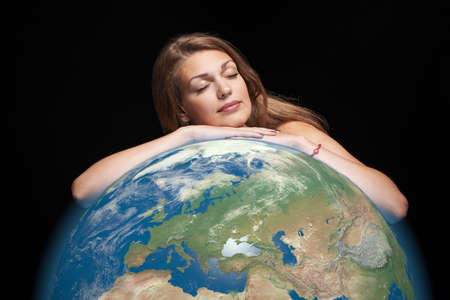 Dreaming beautiful woman hugging earth globe in her hands with closed eyesの写真素材