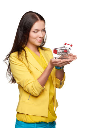 Smiling casual woman standing with small empty shopping cart basket on her palmの写真素材