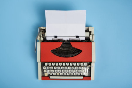 Top view of red vintage typewriter with white blank paper sheetの写真素材