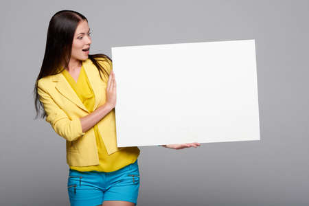 Surprised girl holding empty whiteboardの写真素材