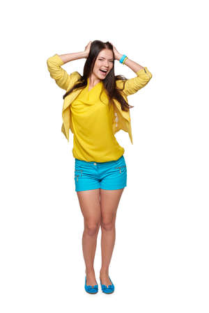 Full length of happy young girl in yellow and blue clothes screaming of joy with hands in hair, isolated on white backgroundの写真素材