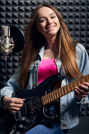 Girl musician in recording studio playing electric guitarの写真素材