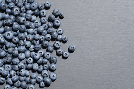 Food background. Ripe blueberries scattered on slate plate .