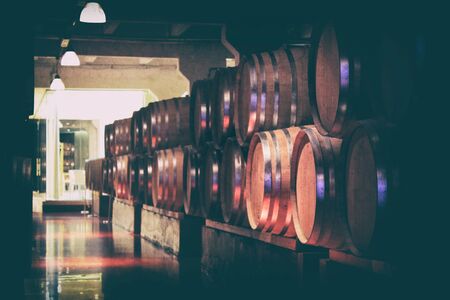 Oak barrels with wine in dark cellar. Modern production of wine with the observance of age-old traditions. Noises and large grain - stylization under the film. Soft focus.の写真素材
