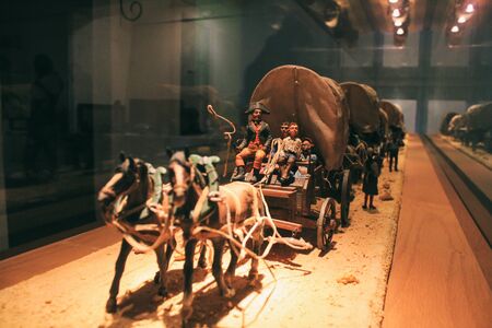 Miniature convoy with horse carts and figures of people. The first Europeans discover America. Noises and large grain - stylization under the film. Soft focus.のeditorial素材