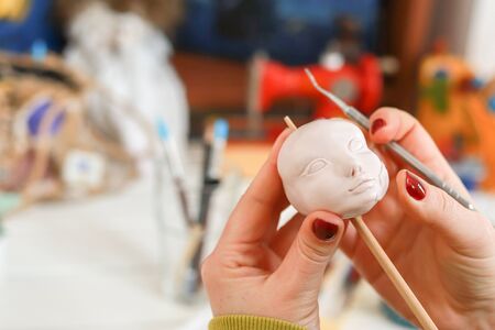 The artist making a new doll face at the toy factory.  The master artist processes the doll's head....