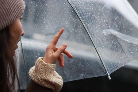 girl is painting the heart on a foggy surface in the rain under an umbrella. Love story conceptの写真素材