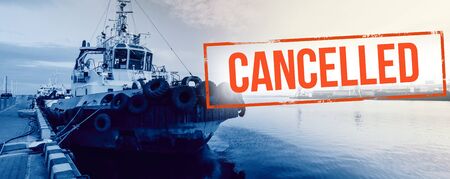 Red inscription "cancelled" on a  blurred blue  background of cargo ship  in sea port. Concept: Global economic crisis, reduction of trade, suspension of carriage, halting production due to a pandemicの写真素材
