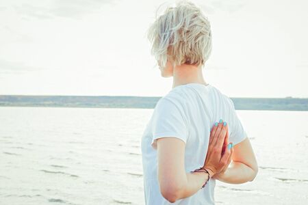 Young  woman doing morning exercises on coast  in summer.