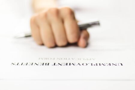 Close-up of a person's hand filing social security benefits application form.の写真素材