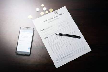 Unemployment benefit form on the table phone and pen.の写真素材