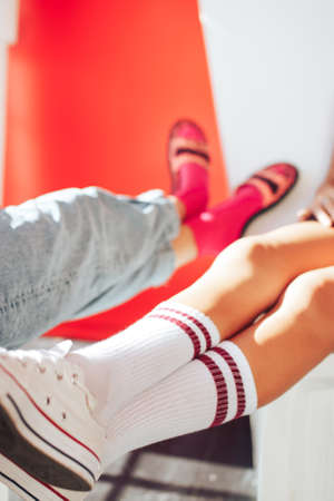 girlfriends sitting on the wall - white sneakers close-up.の写真素材