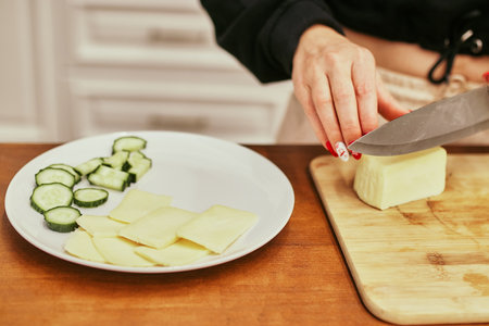 Young woman cuts vegetables and fruits in the kitchen at home. Fresh fruits and vegetables on the kitchen table. ingredients for cooking. close upの写真素材