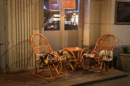 Rustic Sidewalk Cafe with Wooden Tables, Flower Pot and Plaids on Wicker Chair Outdoorsの写真素材