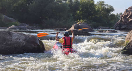 A man rowing inflatable packraft on whitewater of mountain river. Concept: summer extreme water sport, active rest, extreme rafting.の写真素材