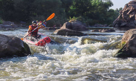 A man rowing inflatable packraft on whitewater of mountain river. Concept: summer extreme water sport, active rest, extreme rafting.の写真素材