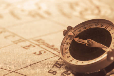 Magnetic old compass on world vintage map.Travel, geography, navigation, tourism and exploration concept background.Macro shot, shallow focus.の写真素材