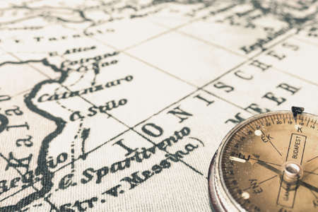 Magnetic old compass on world vintage map.Travel, geography, navigation, tourism and exploration concept background.Macro shot, shallow focus.の写真素材