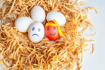 funny and funny multi-colored Easter eggs with painted faces - emoticon decorated with ribbons on a...
