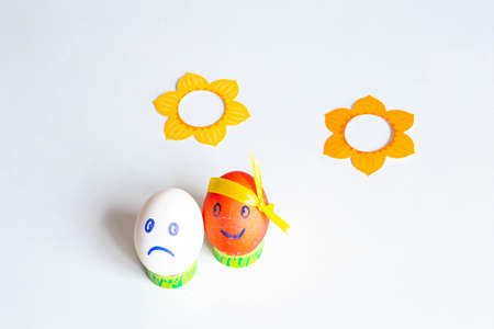 funny and funny multi-colored Easter eggs with painted faces - emoticon decorated with ribbons on a white background close-upの写真素材