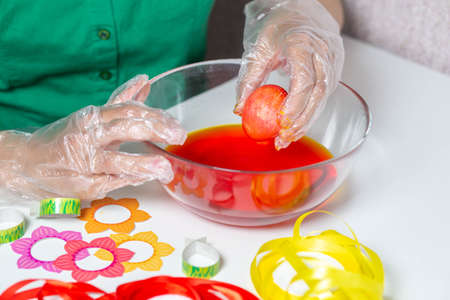 female hands in pastry chef's gloves and a green blouse decorate eggs for the holiday