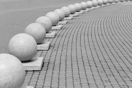 gray sidewalk close-up framed by gray concrete ballsの写真素材
