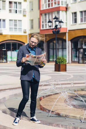 a girl in a gray jacket and brown glasses with surprise and a smile reads the fresh press on the...