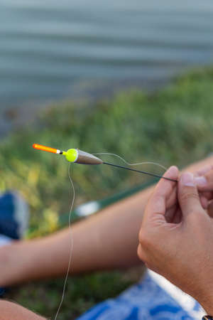 A man catches a fish, pulls a fishing rod while fishing from a lake or pond with space for text