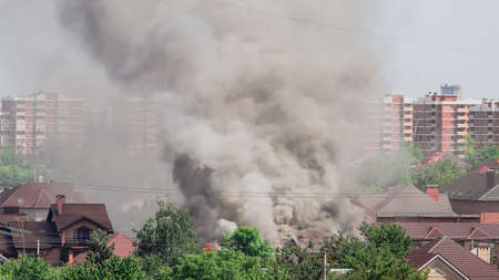 Pillar of black smoke from a burning wooden house.