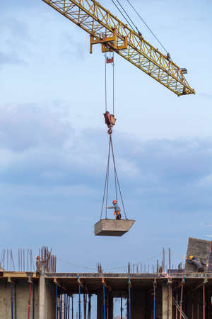 Russia, Krasnodar - 23.08.2021. Hydraulic booms of tower cranes and workers pour concrete into the foundation.のeditorial素材