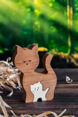 Wooden puzzle in the form of a handmade cat family on the background of the forestの写真素材