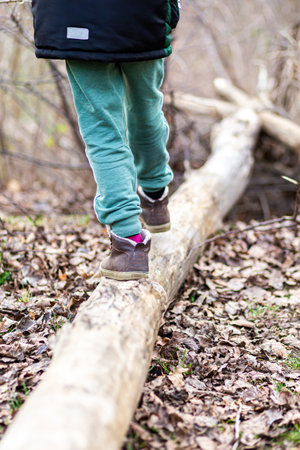 feet in teenage shoes take a step on a log in a city parkの写真素材