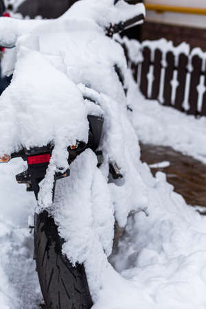 A motorcycle in the snow is parked in the courtyard of the houseの写真素材