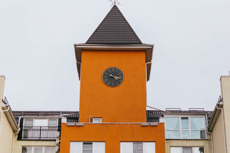 Clock on a high orange tower in orange color in Europe close-up.の写真素材