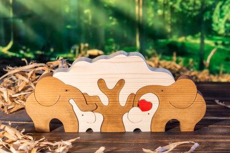 Wooden puzzle in the form of a family of handmade elephants on the background of the forestの写真素材