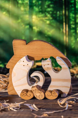 Wooden puzzle in the form of a handmade cat family on the background of the forestの写真素材
