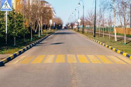 Yellow pedestrian crossing on an asphalt road.