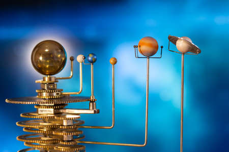 Model of the solar system made of brass close-up on a blue background.