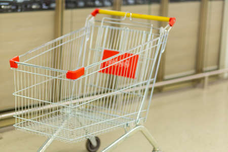 Empty cart on wheels for groceries in a hypermarket on a blurred backgroundの写真素材