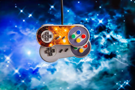 Two joysticks hang on wires on a blurred space background