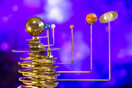 Model of the solar system made of brass close-up on a blue background.
