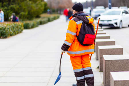 Russia, Krasnodar - 03.21.2022. Close-up of a cleaning lady in overalls and gloves holding dustpan.の写真素材