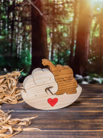Wooden puzzle in the form of a family of handmade elephants on the background of the forestの写真素材