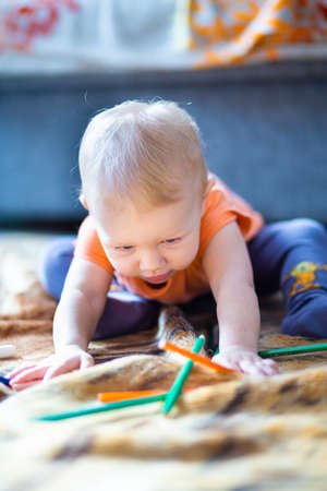 A child plays with rainbow-colored pencils on a blurred background.