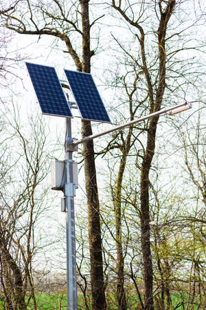 Close-up of a modern photovoltaic solar array against the background of trees and blue sky.