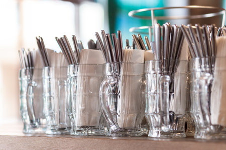 Cutlery and napkins are arranged in a beer mug and lined up for customers at the barの写真素材