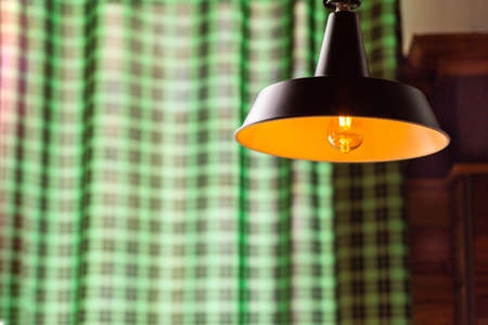 Pendant lamp as an interior element in the loft style against the background of checkered curtains in a cafe.の写真素材