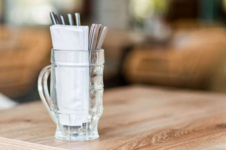 Cutlery and white napkins in a beer mug on a table in a street cafe.の写真素材