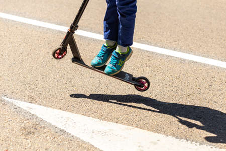 Close-up of the legs of a child riding a scooter on the road